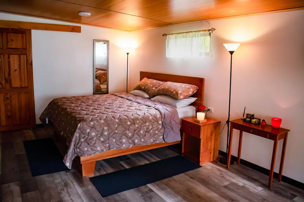 Cama con cabecera de madera, lámparas de pie y techo de madera dentro del Pizote Apartment, Santa Elena