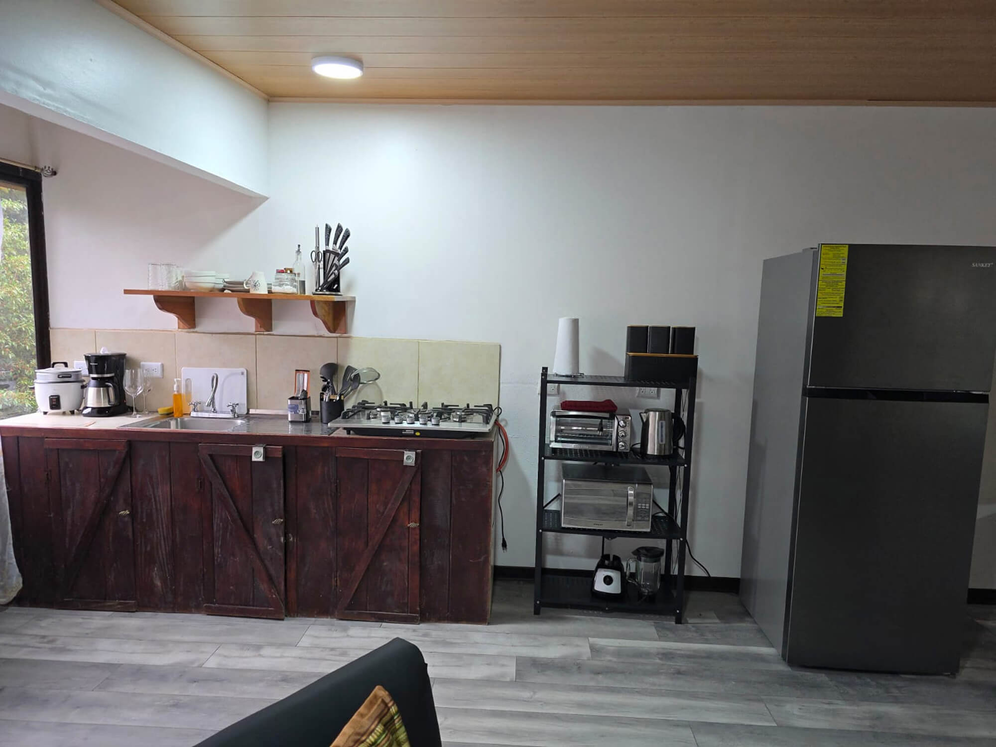 Kitchen counter with coffee maker, gas hob, utensils and fridge