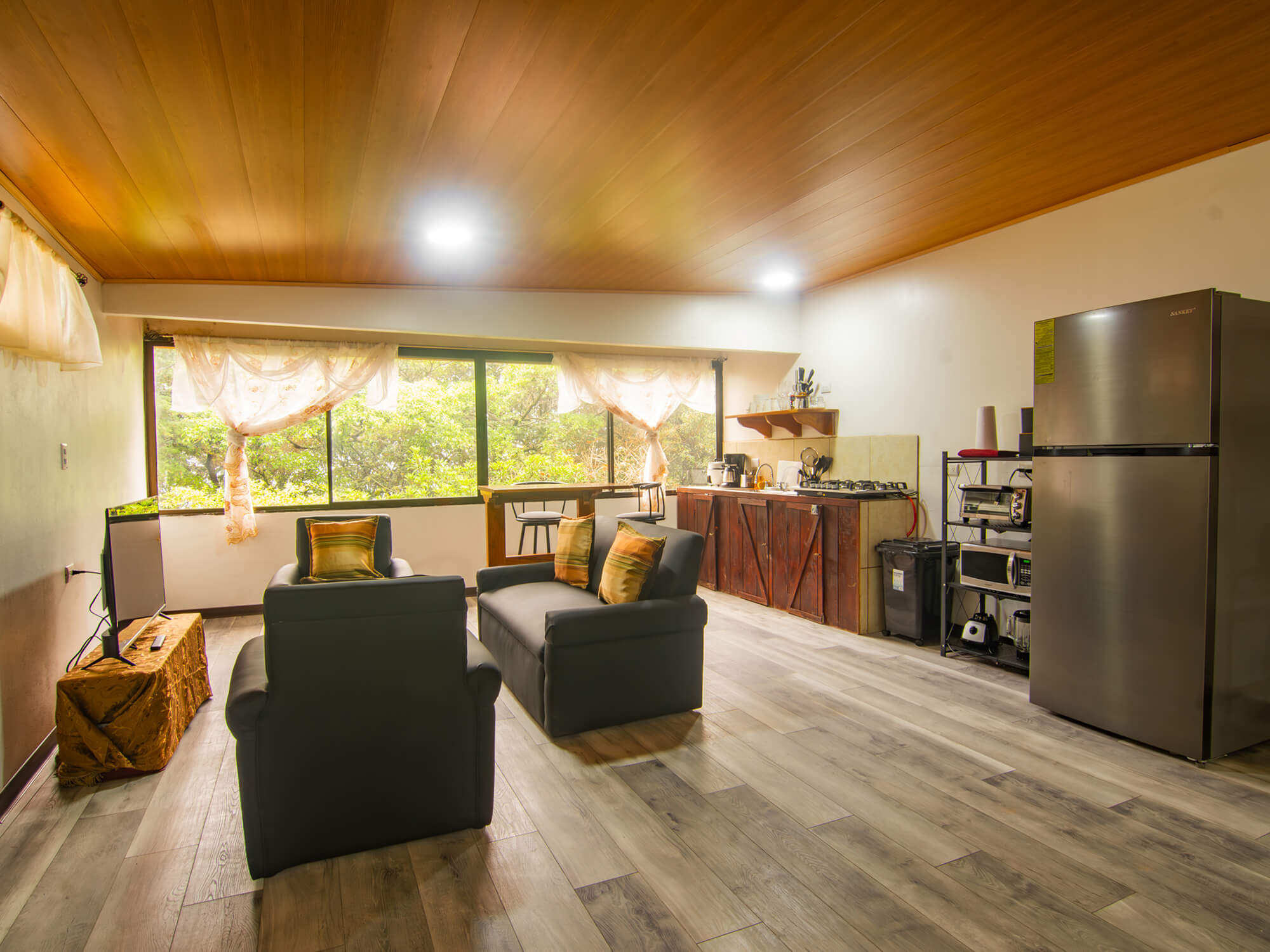 Living area with two armchairs, full-size fridge and kitchen counter