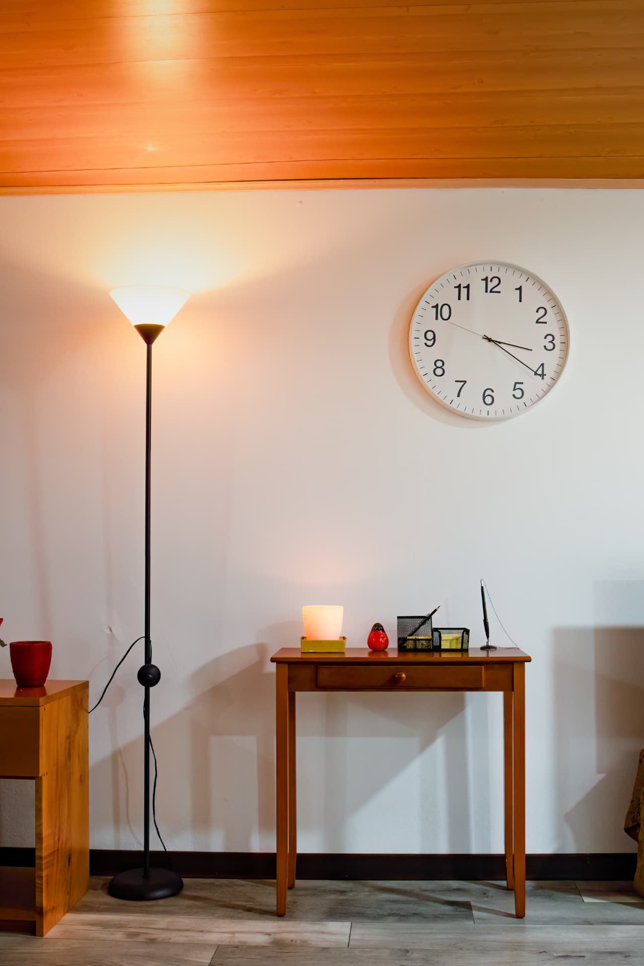Writing table with lamp and desk accessories under the wall clock in the studio