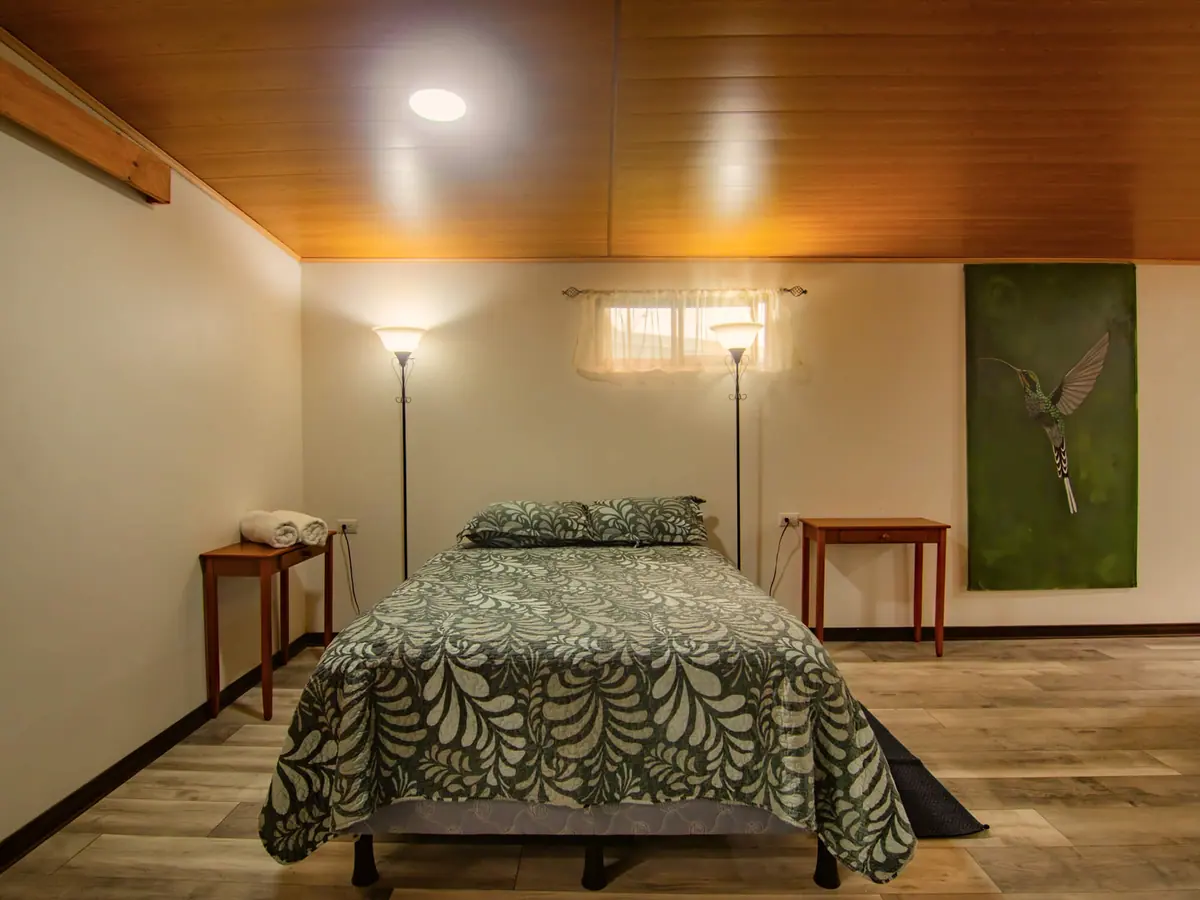 Cama con ropa de cama de hojas bajo el techo de madera del Pizote Apartment