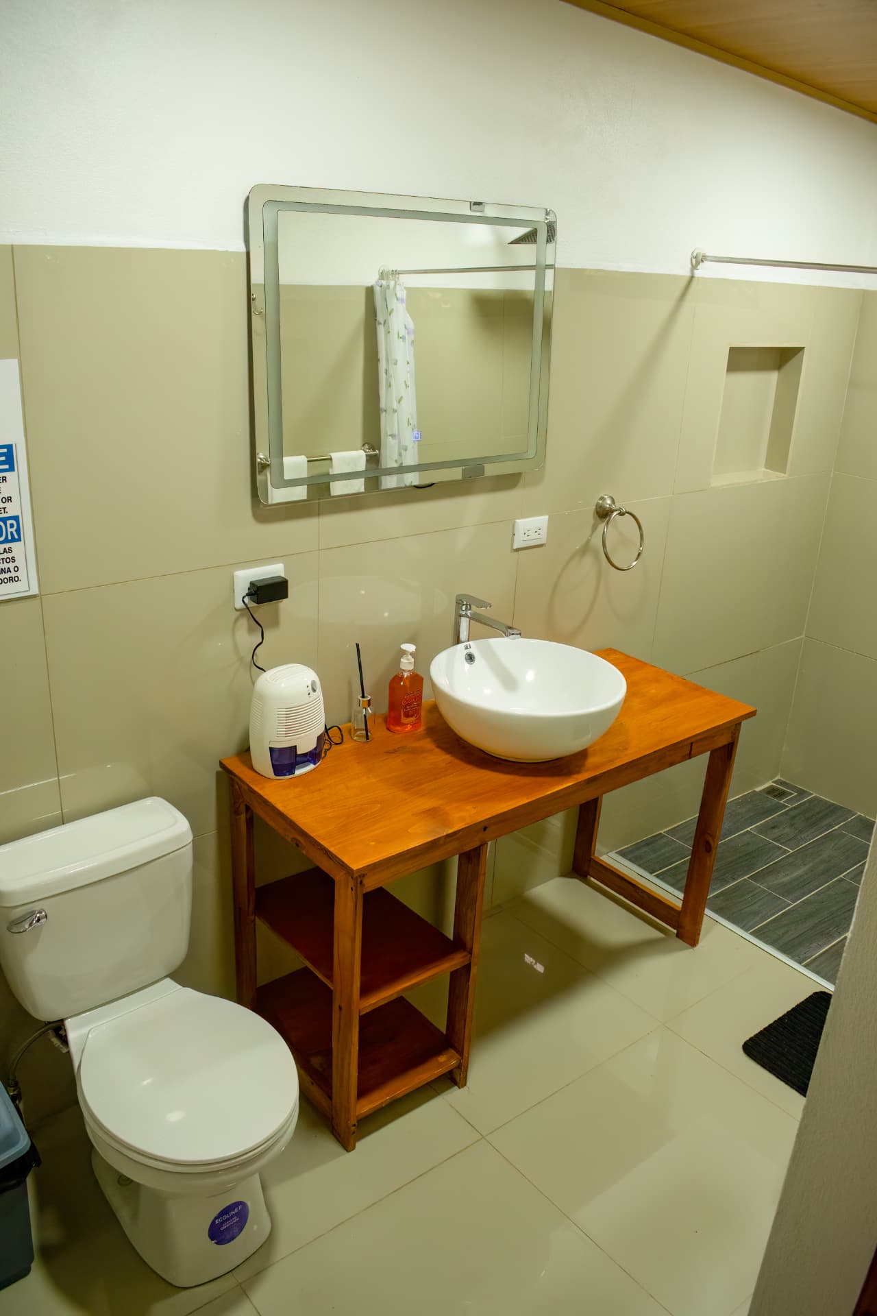Private bathroom of Pizote Apartment with vessel sink on a wooden table, mirror and walk-in shower