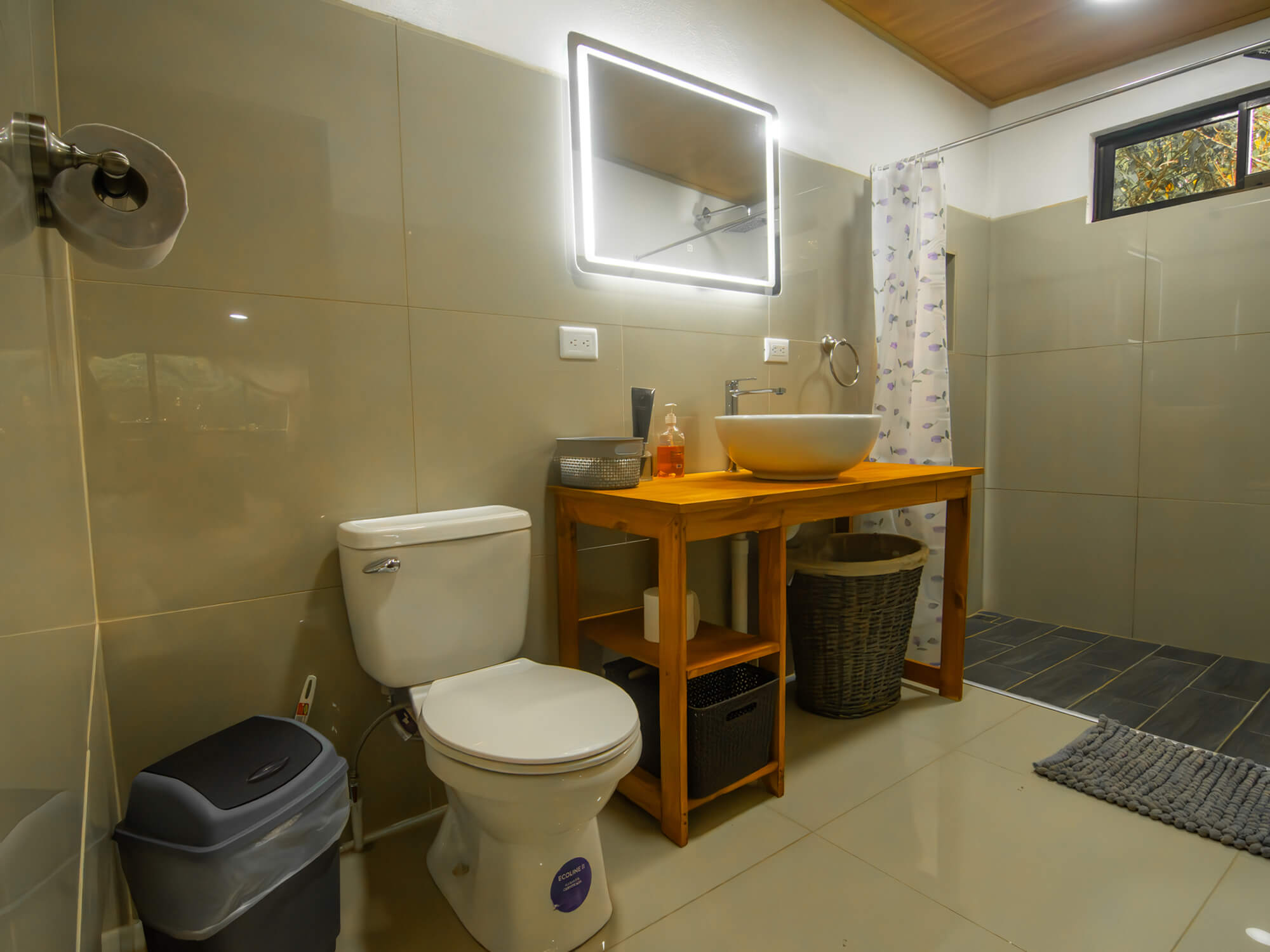 Toilet, laundry basket and vanity in the tiled private bathroom