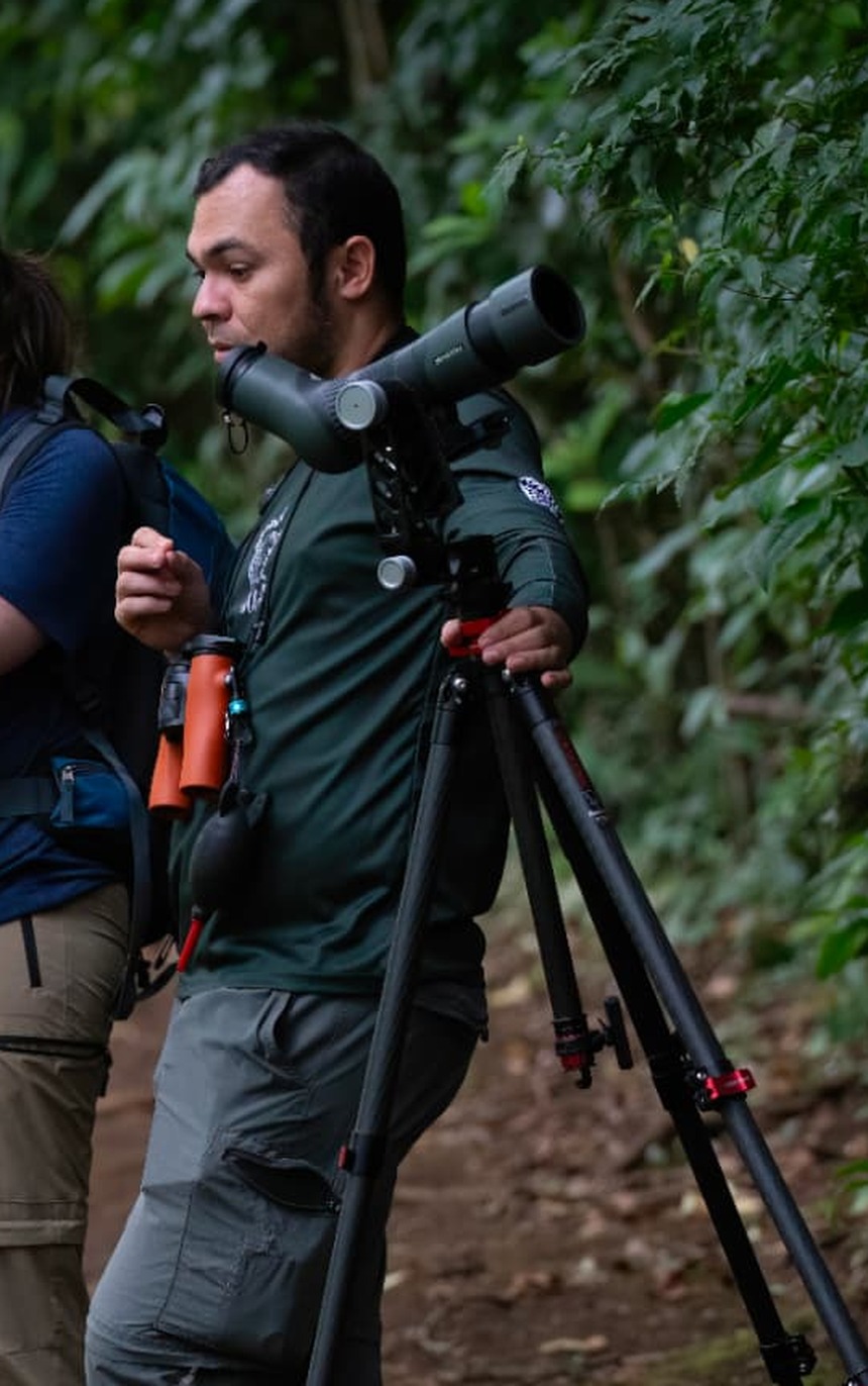 Oscar Castillo Mejía, founder and lead naturalist guide of Nasua Tours, carrying his spotting scope on a Monteverde forest trail