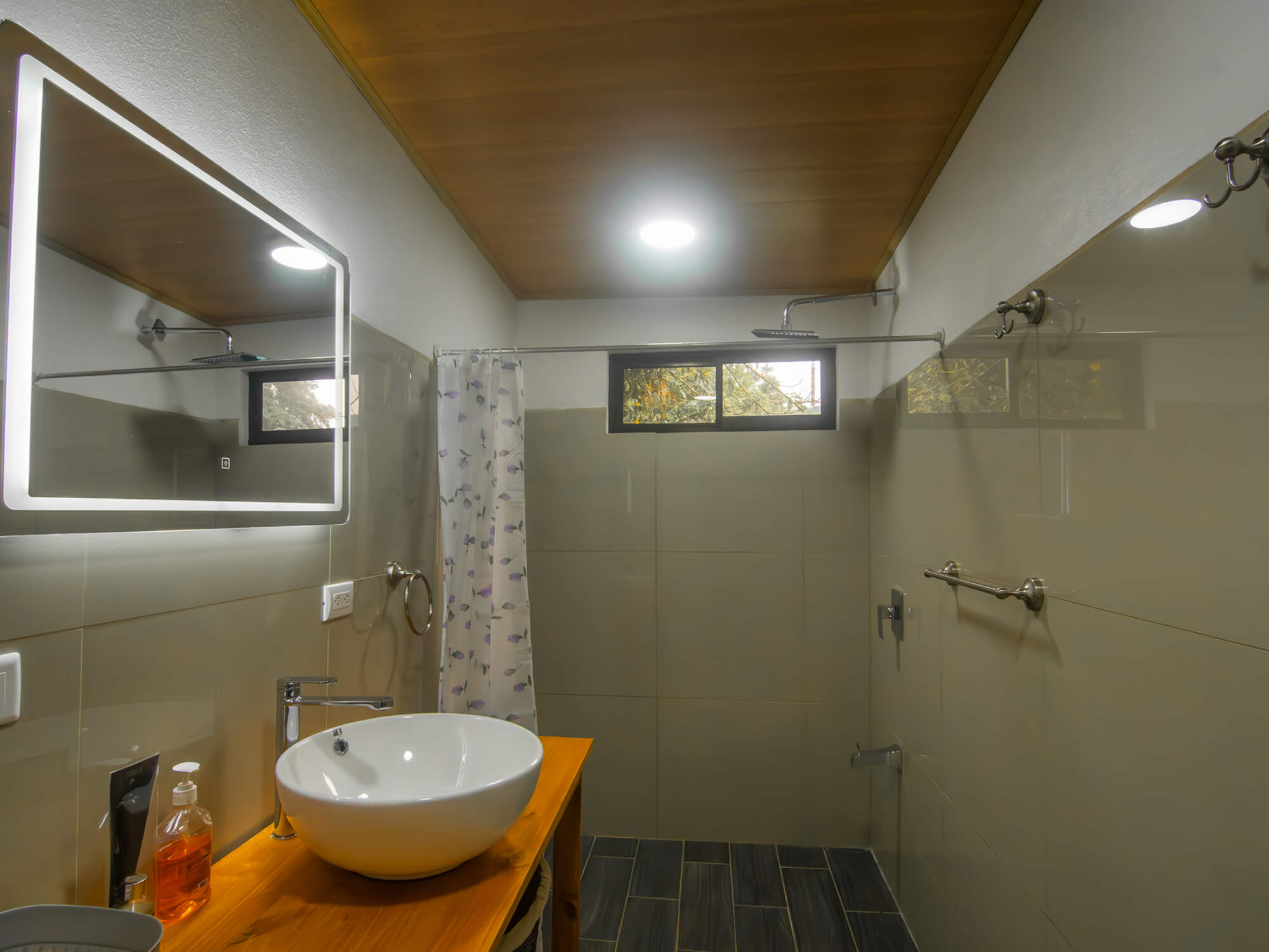 Hot-water shower area next to the wooden vanity in the private bathroom