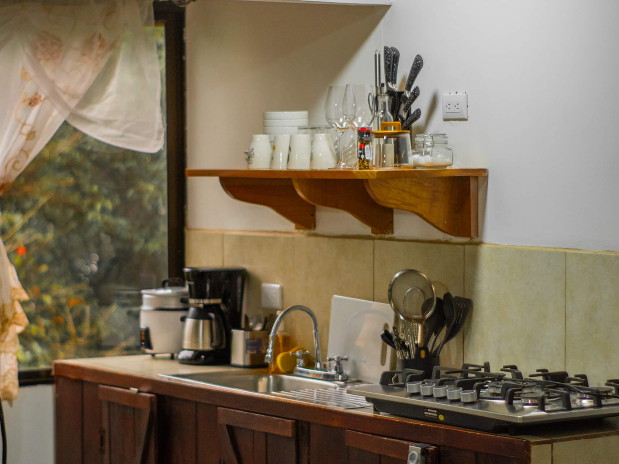 Kitchen shelves with cups, kettle and cookware next to the window