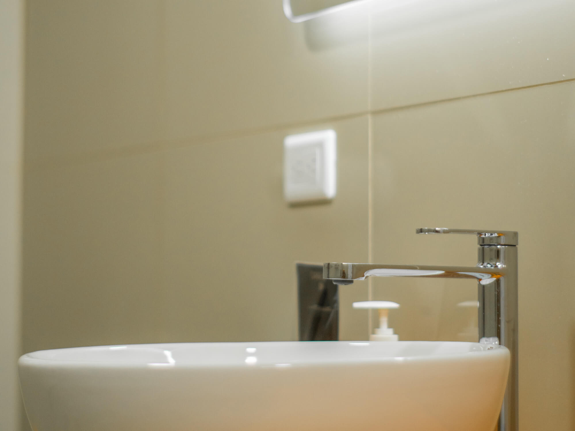 Vessel sink with mixer tap and hand soap in the private bathroom