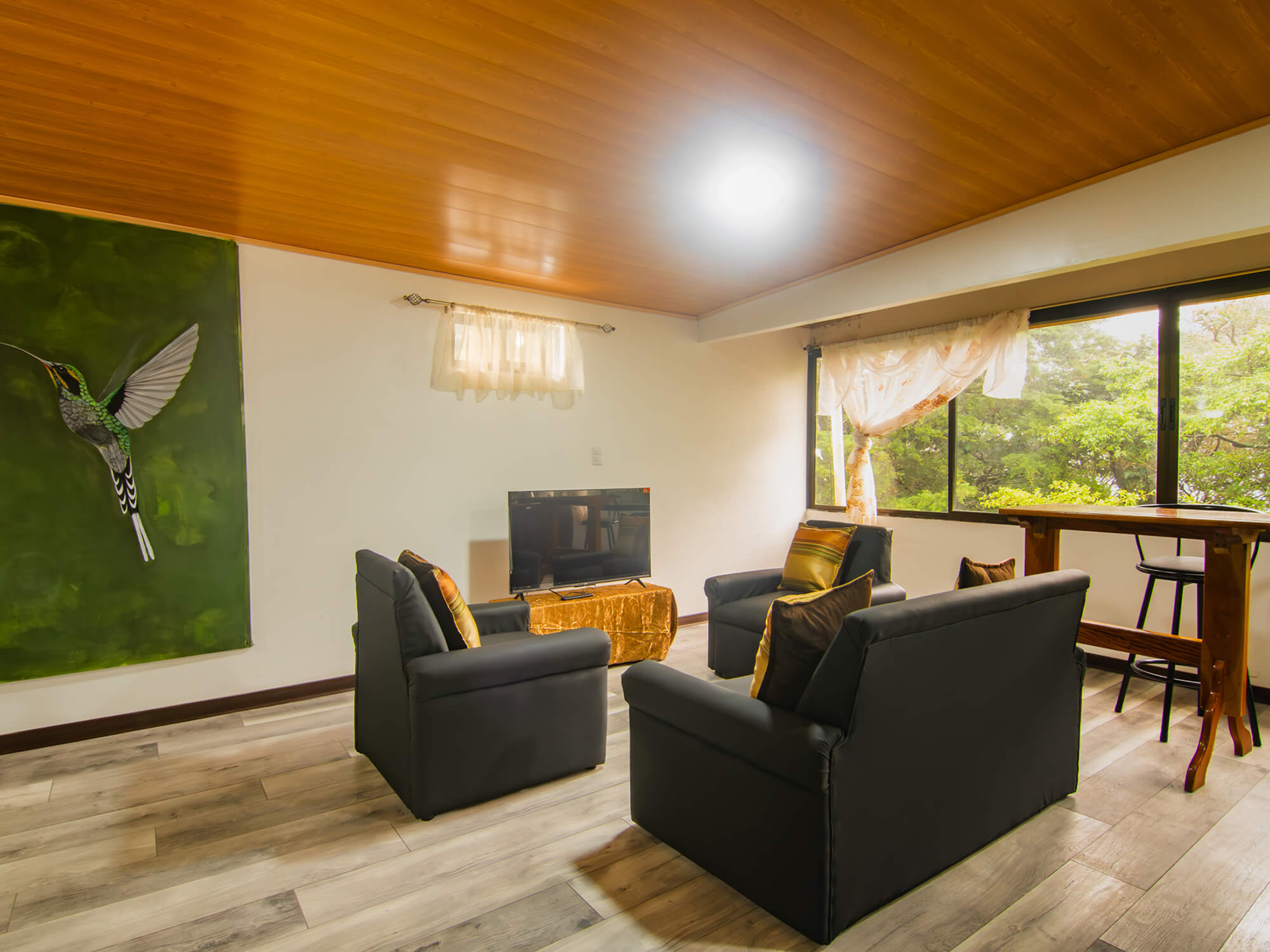 Seating area facing the window wall with forest views in Pizote Apartment