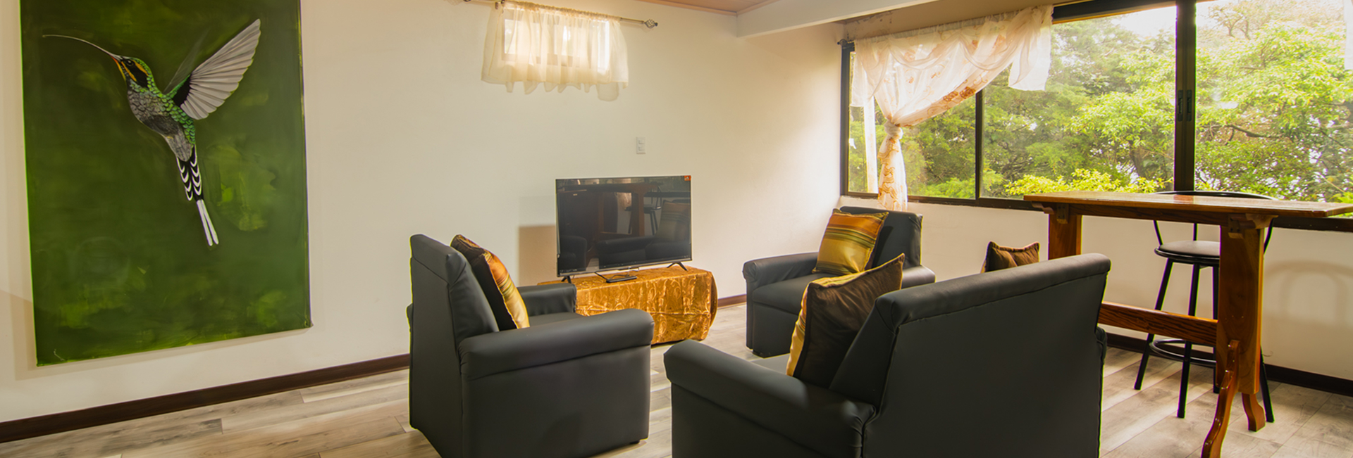 Dining bar with stools beside the window and hummingbird artwork in the Pizote Apartment studio