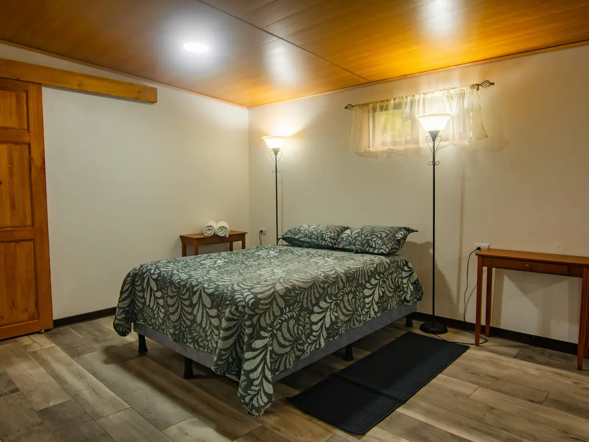 Zona de dormir del estudio con piso tipo madera y mesa de noche