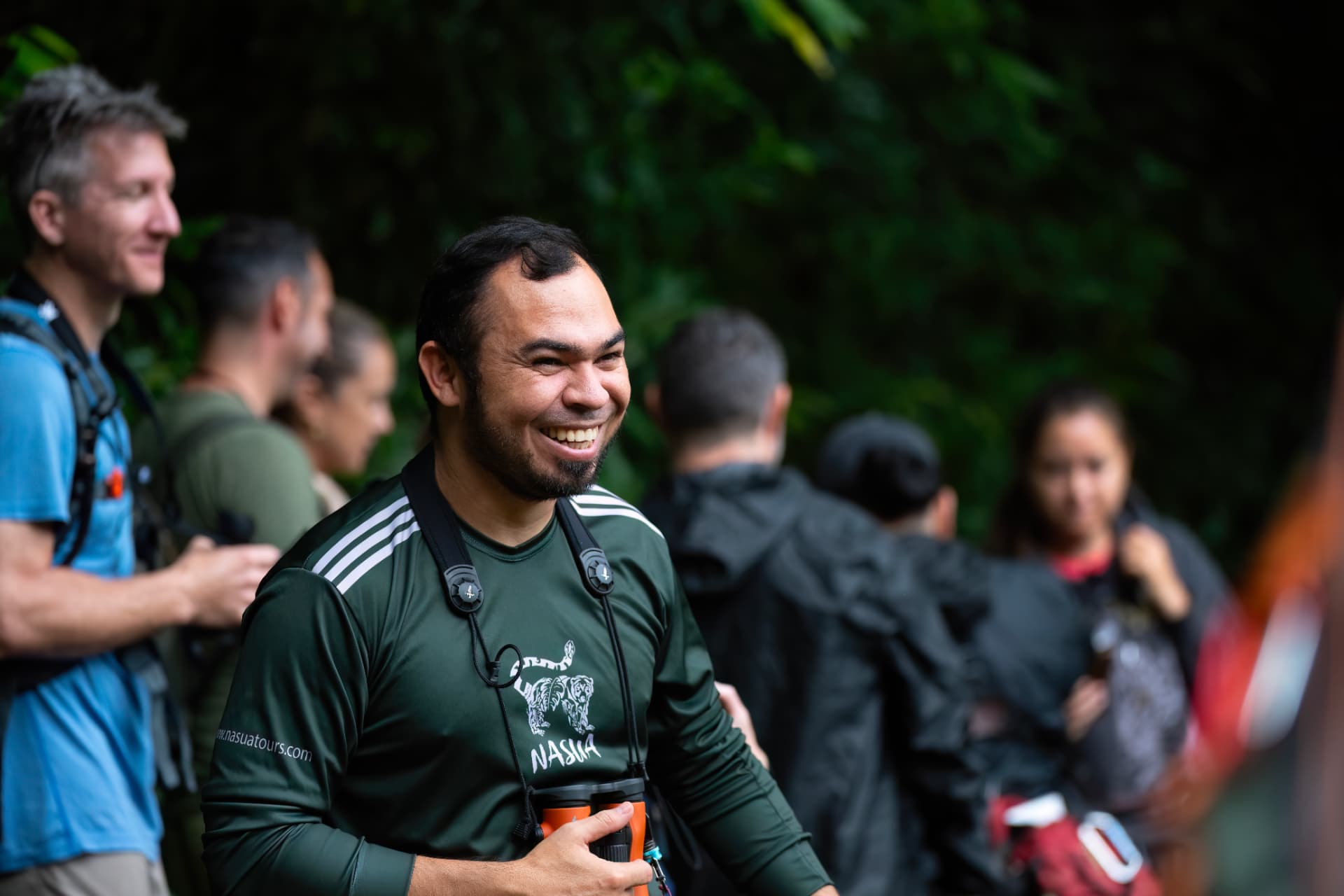 Oscar Castillo Mejía Mejía, founder and lead naturalist guide of Nasua Tours, smiling with binoculars on a Monteverde trail
