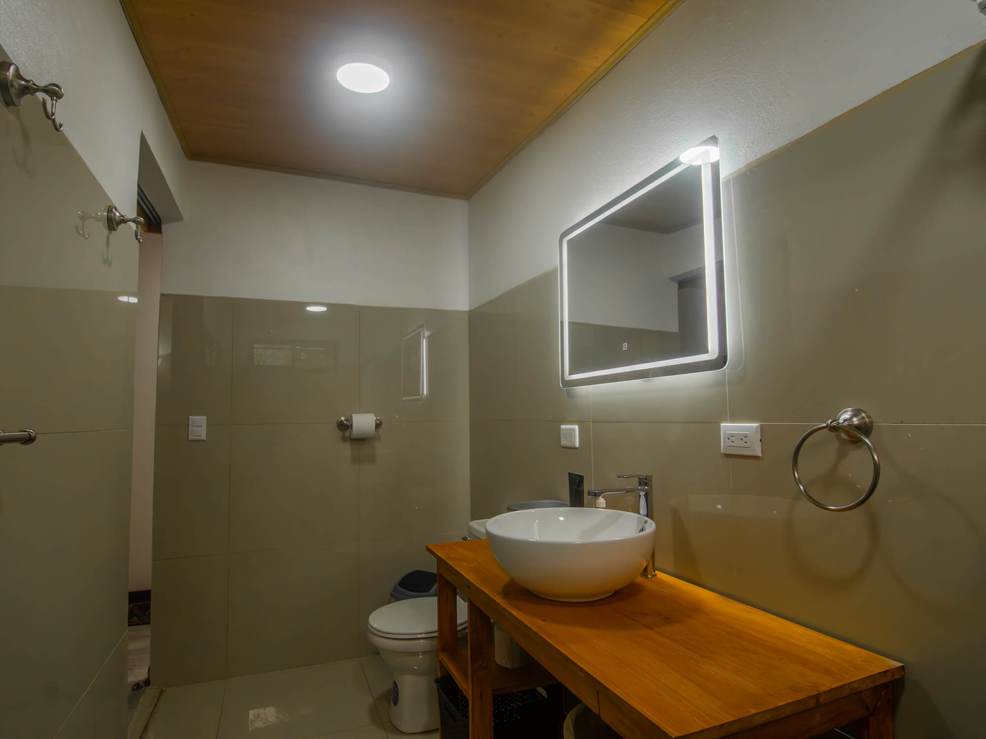 Bathroom with backlit mirror, wooden vanity and glass shower screen