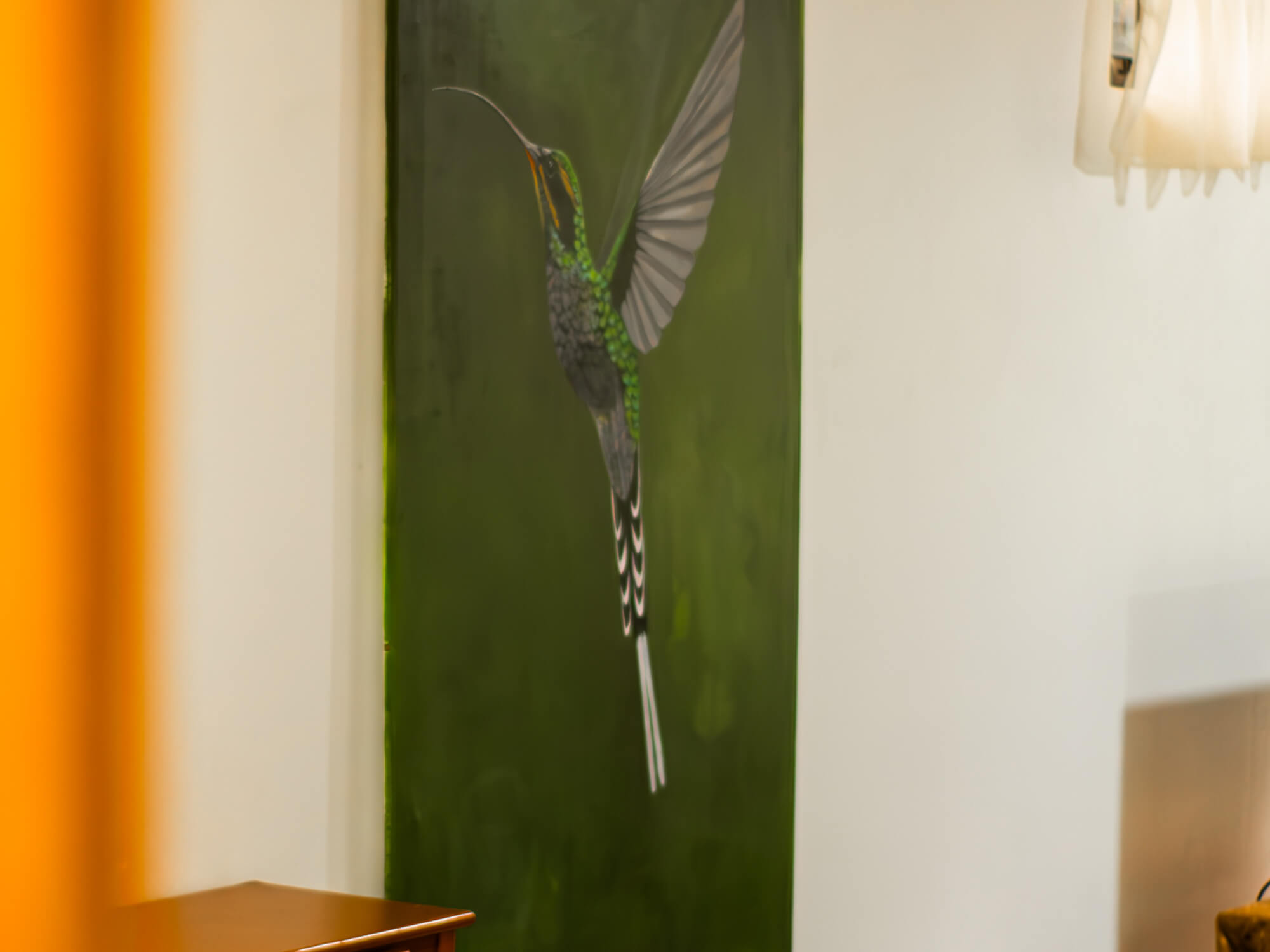 Hummingbird painting on the green accent wall of Pizote Apartment