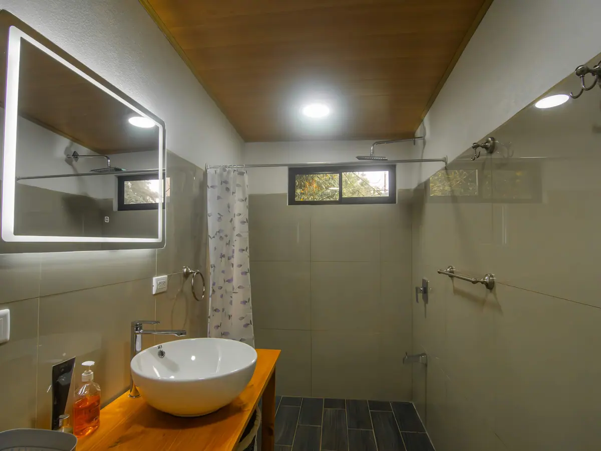 Zona de ducha con agua caliente junto al mueble de madera del baño privado