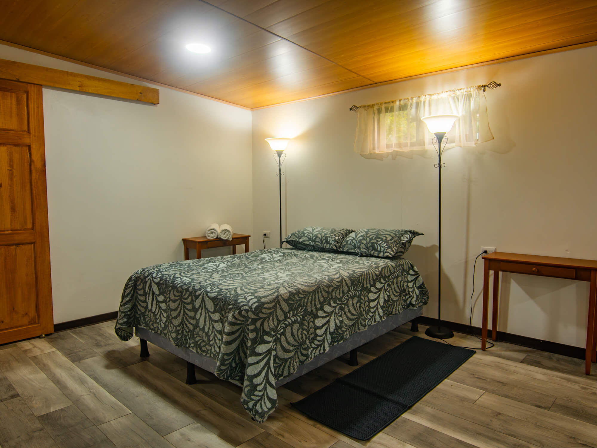Sleeping area of the studio with wood-look flooring and bedside table